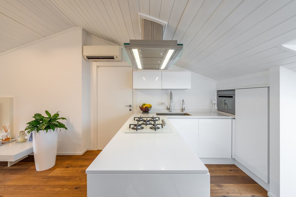 На фото: угловая кухня-гостиная в скандинавском стиле с врезной мойкой, плоскими фасадами, белыми фасадами, белым фартуком, паркетным полом среднего тона, полуостровом и белой столешницей