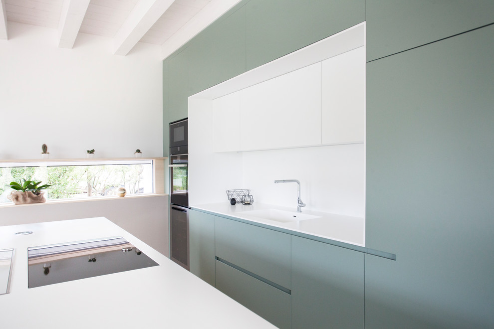 Zweizeilige Nordische Küche mit integriertem Waschbecken, grünen Schränken, Küchenrückwand in Weiß, schwarzen Elektrogeräten, Kücheninsel und weißer Arbeitsplatte in Sonstige