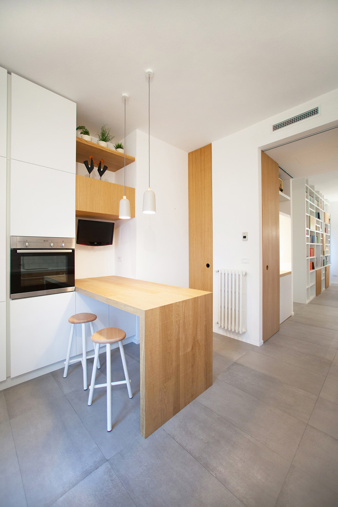 Idéer för funkis kök, med grått golv, släta luckor, vita skåp, träbänkskiva, rostfria vitvaror och en halv köksö
