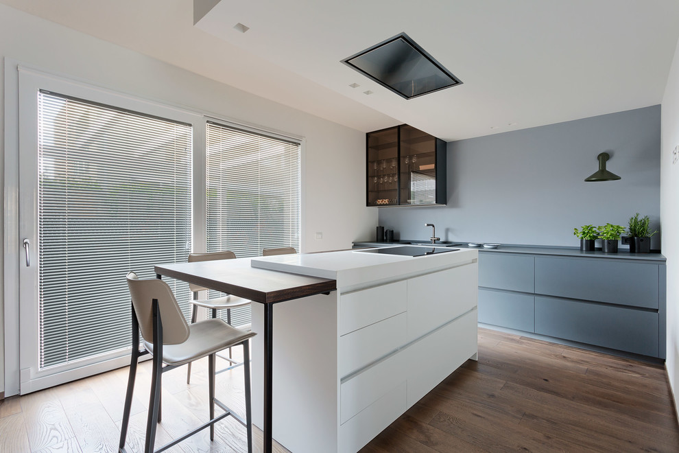 This is an example of a scandi kitchen in Bologna with flat-panel cabinets, grey cabinets, grey splashback, medium hardwood flooring, an island and grey worktops.