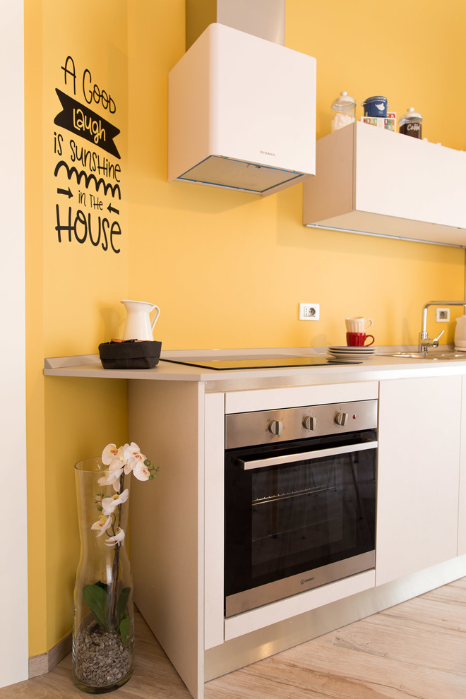 Immagine di una piccola cucina minimal con lavello da incasso, ante lisce, ante beige, top in laminato, elettrodomestici in acciaio inossidabile, pavimento in gres porcellanato e pavimento beige
