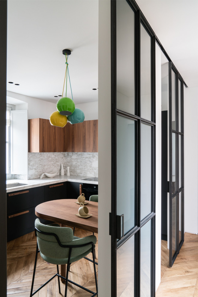 This is an example of a medium sized contemporary l-shaped enclosed kitchen in Turin with an integrated sink, flat-panel cabinets, black cabinets, grey splashback, integrated appliances, light hardwood flooring, no island, brown floors and grey worktops.