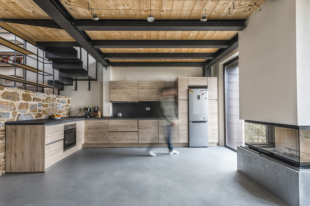 Inspiration for a farmhouse l-shaped concrete floor and gray floor kitchen remodel in Florence with flat-panel cabinets, light wood cabinets, black backsplash, stainless steel appliances, no island and black countertops