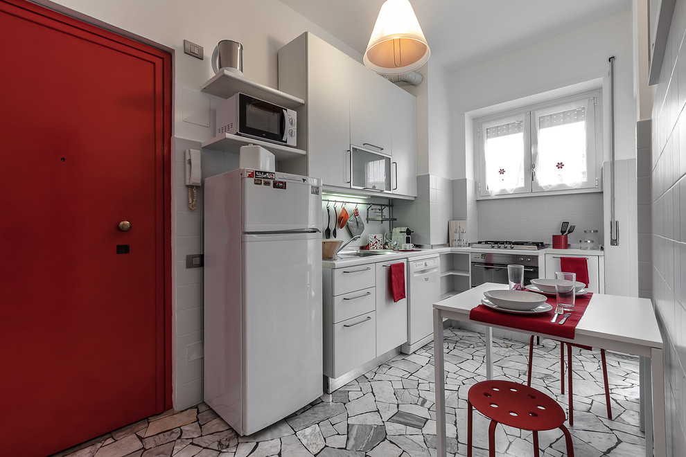 Photo of a medium sized contemporary l-shaped kitchen/diner in Milan with flat-panel cabinets, grey cabinets, white splashback, stainless steel appliances, grey floors and no island.