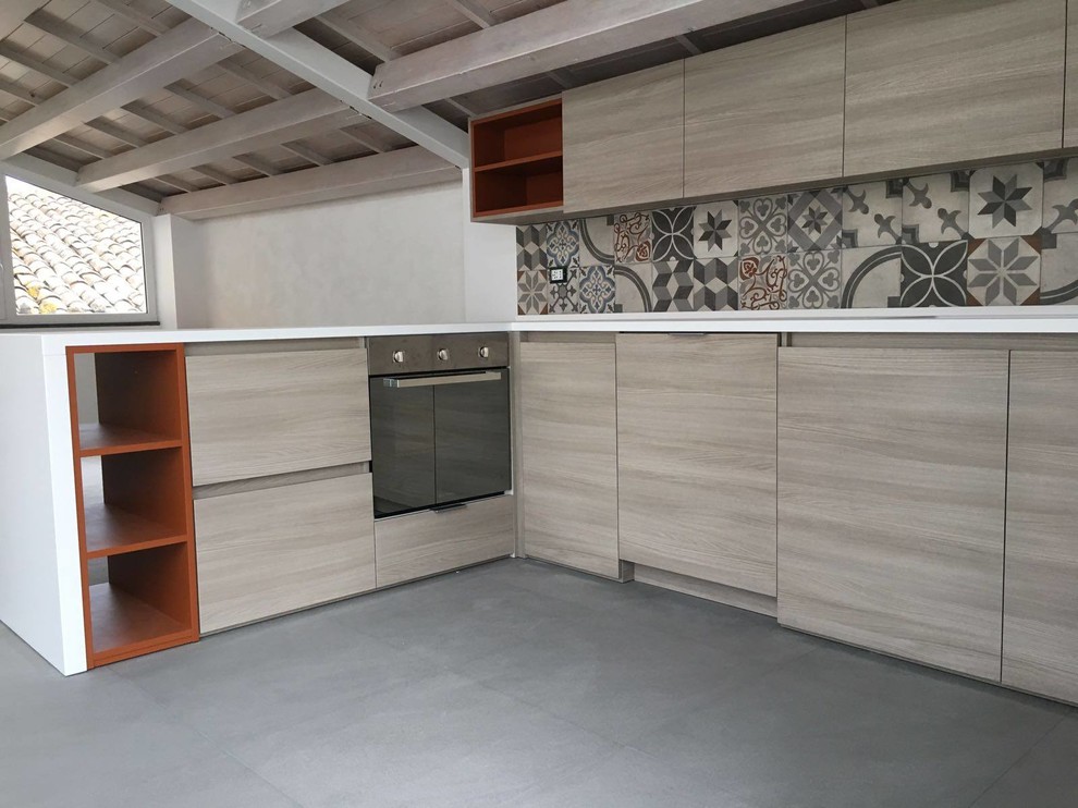 Large contemporary l-shaped open plan kitchen in Catania-Palermo with an integrated sink, flat-panel cabinets, light wood cabinets, composite countertops, porcelain flooring, a breakfast bar, grey floors and white worktops.