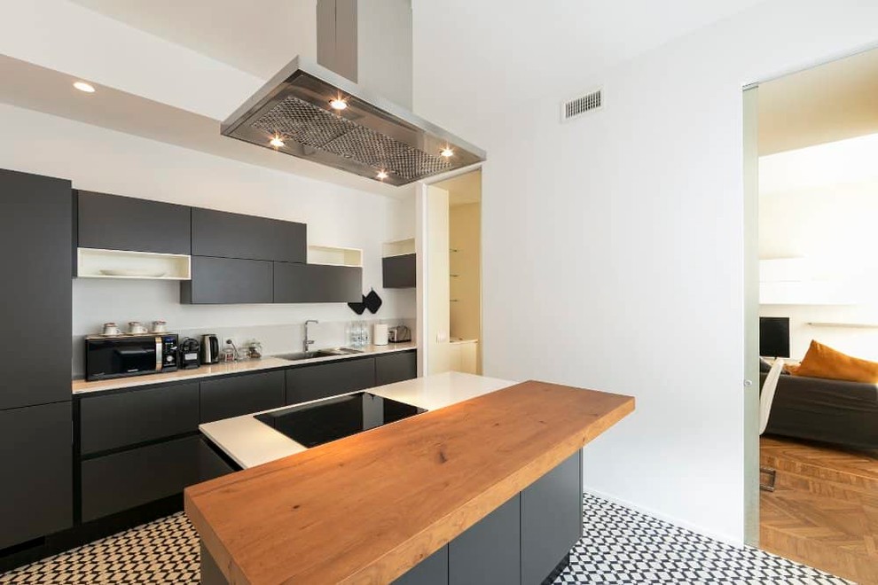 Example of a large trendy single-wall cement tile floor enclosed kitchen design in Milan with an integrated sink, flat-panel cabinets, gray cabinets, quartzite countertops, white backsplash, marble backsplash, stainless steel appliances, white countertops and an island