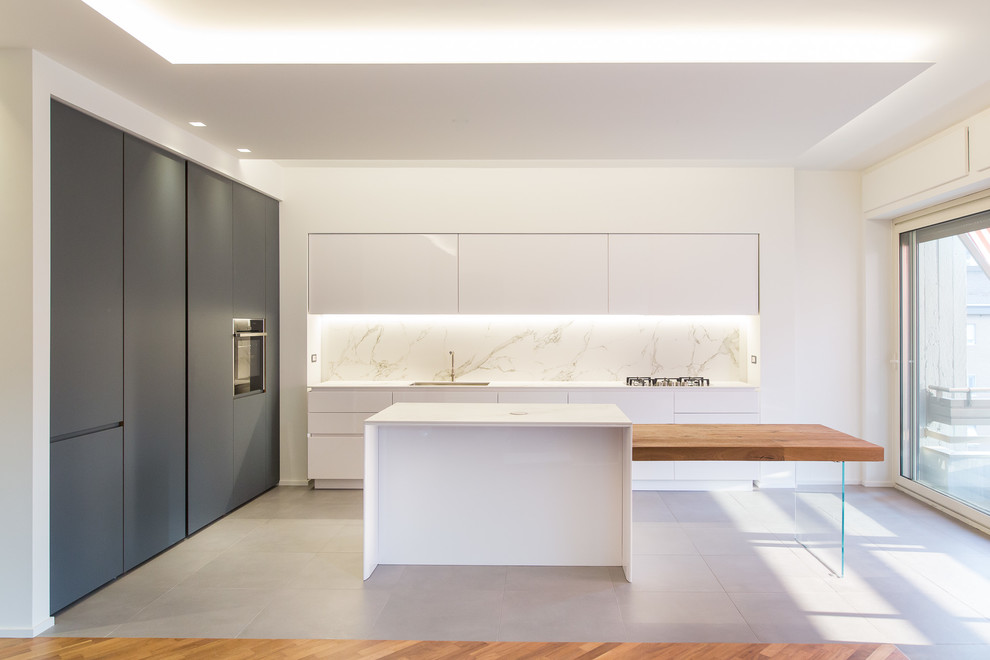 Moderne Küche mit flächenbündigen Schrankfronten, weißen Schränken, Küchenrückwand in Weiß und weißer Arbeitsplatte in Sonstige