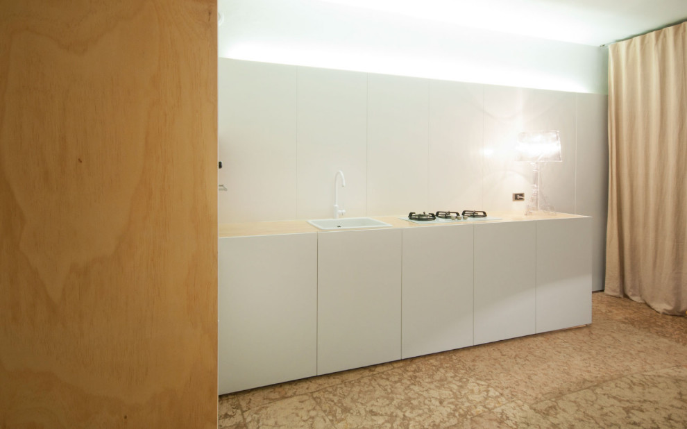 Modelo de cocina comedor contemporánea pequeña con puertas de armario blancas, encimera de madera, suelo de piedra caliza, fregadero de un seno y armarios con paneles lisos