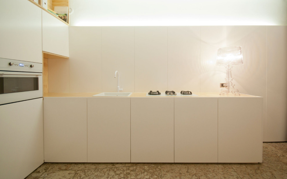 他の地域にあるコンテンポラリースタイルのおしゃれなダイニングキッチン (シングルシンク、フラットパネル扉のキャビネット、白いキャビネット、ライムストーンの床) の写真