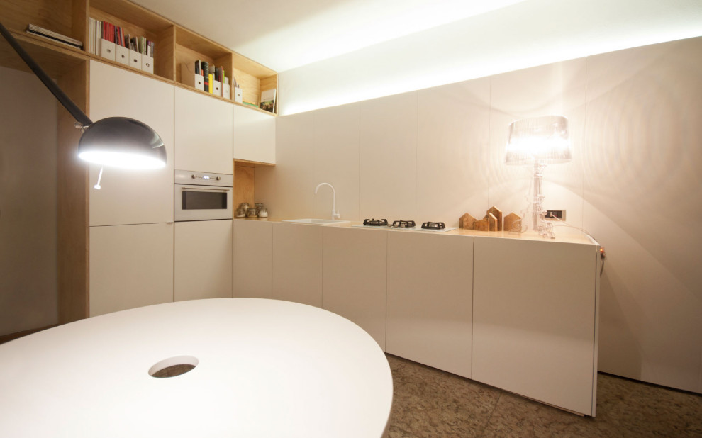 Idee per una cucina abitabile minimal con lavello a vasca singola, ante lisce, ante bianche e pavimento in pietra calcarea