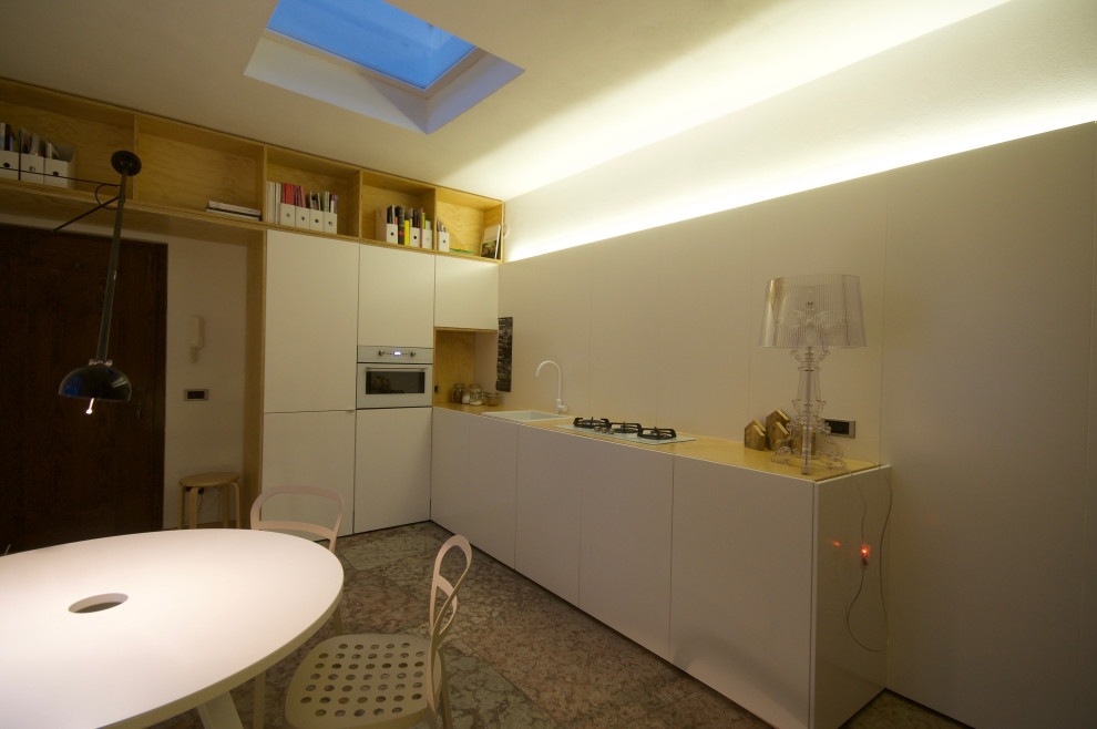 На фото: кухня в современном стиле с обеденным столом, одинарной мойкой, плоскими фасадами, белыми фасадами и полом из известняка