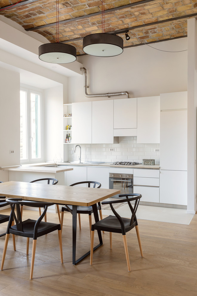 ローマにある中くらいなコンテンポラリースタイルのおしゃれなキッチン (フラットパネル扉のキャビネット、白いキャビネット、白いキッチンパネル、サブウェイタイルのキッチンパネル、シルバーの調理設備、無垢フローリング) の写真