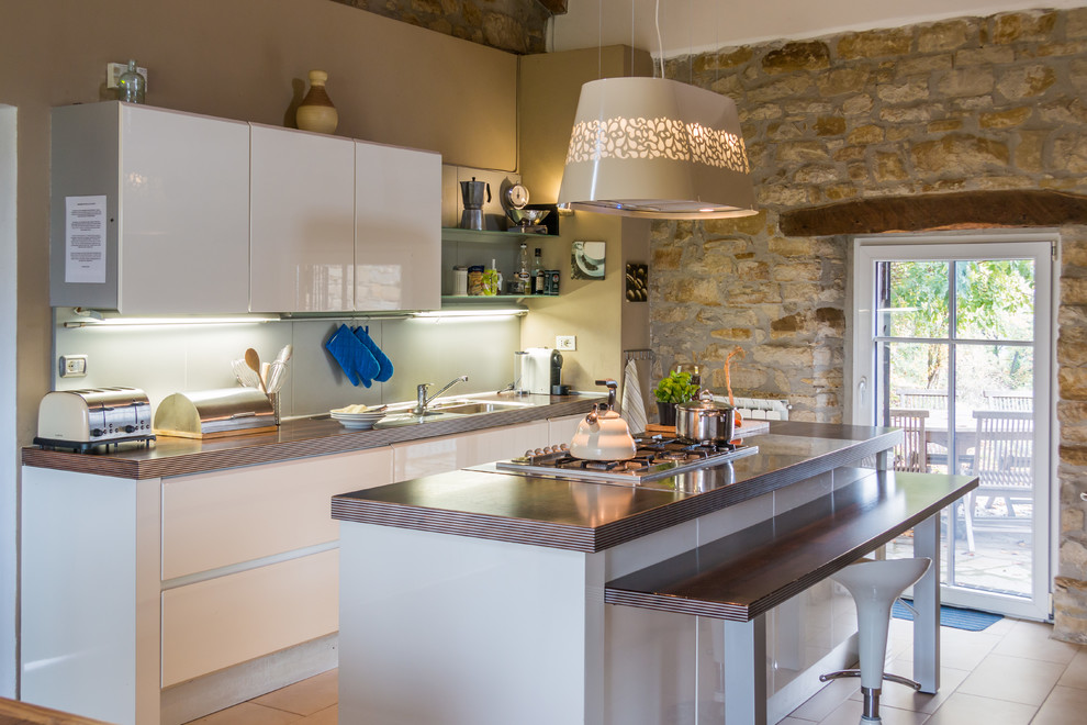 Inspiration for a small contemporary galley porcelain tile and beige floor eat-in kitchen remodel in Turin with white cabinets, an island, an integrated sink, flat-panel cabinets, wood countertops, white backsplash and stainless steel appliances