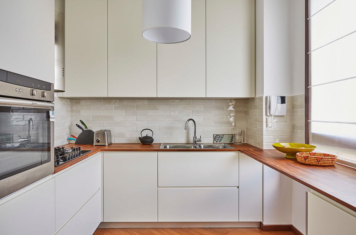 Idéer för att renovera ett avskilt, mellanstort funkis u-kök, med en dubbel diskho, släta luckor, vita skåp, träbänkskiva, beige stänkskydd, stänkskydd i keramik och rostfria vitvaror