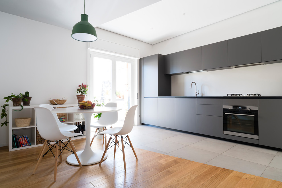 Einzeilige Moderne Wohnküche ohne Insel mit flächenbündigen Schrankfronten, grauen Schränken, Küchengeräten aus Edelstahl, grauem Boden und schwarzer Arbeitsplatte in Catania-Palermo