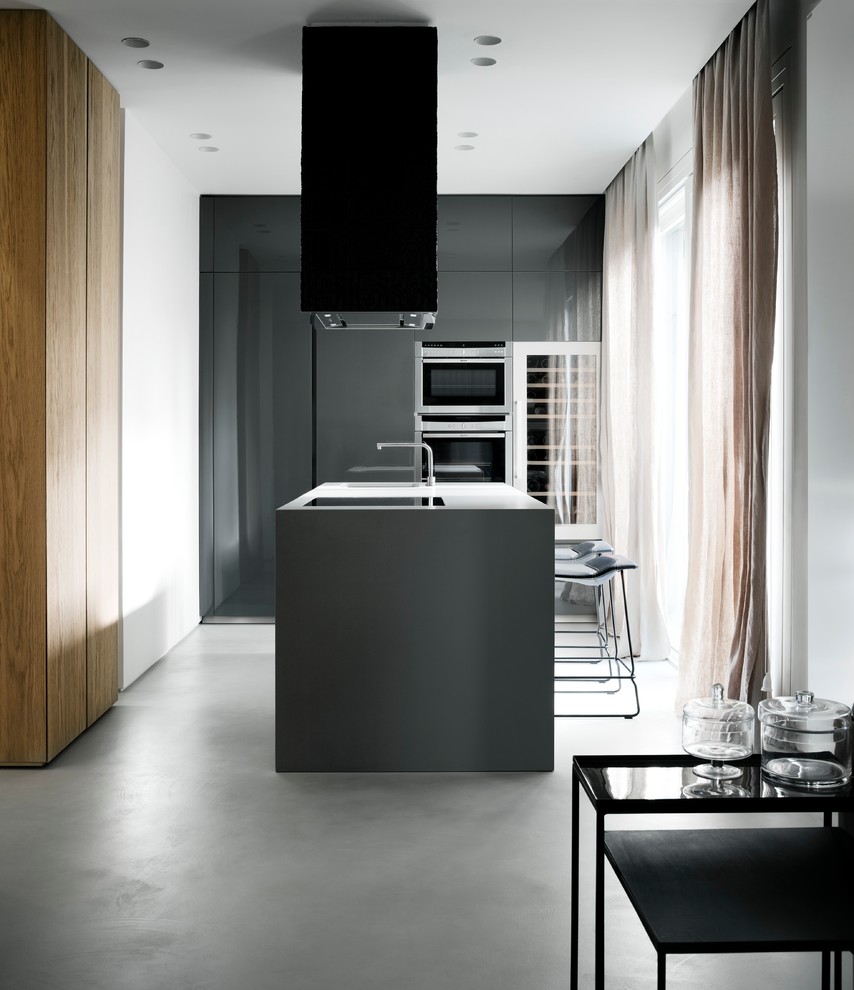 Immagine di un cucina con isola centrale moderno di medie dimensioni con lavello integrato, ante lisce, ante grigie, elettrodomestici in acciaio inossidabile e pavimento in cemento