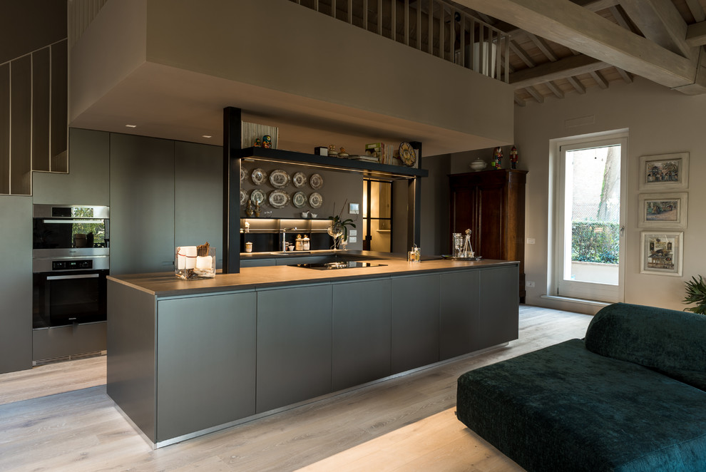 Offene Moderne Küche mit flächenbündigen Schrankfronten, grauen Schränken, hellem Holzboden, Kücheninsel, beigem Boden und grauer Arbeitsplatte in Sonstige