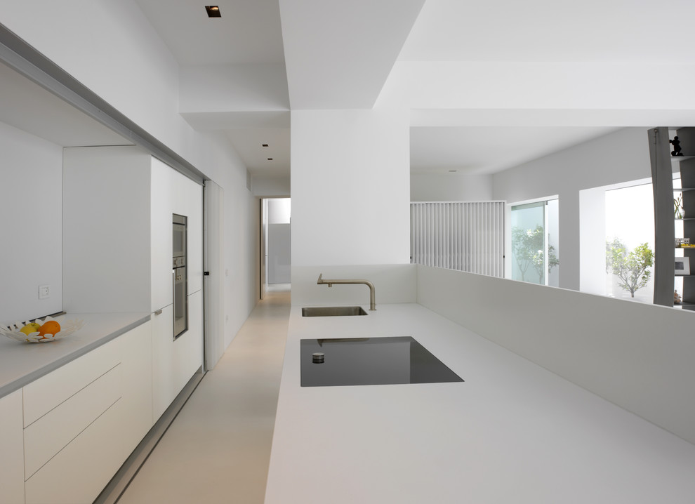Стильный дизайн: параллельная кухня-гостиная среднего размера в современном стиле с плоскими фасадами, белыми фасадами, островом и техникой из нержавеющей стали - последний тренд