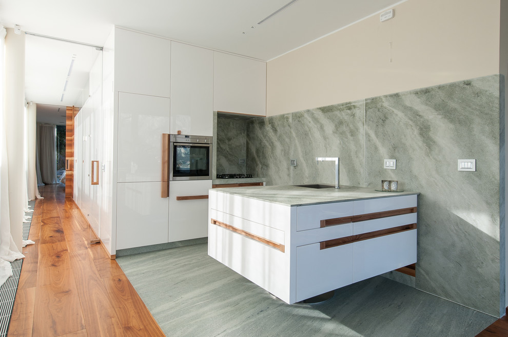 Idéer för att renovera ett mellanstort funkis linjärt kök, med en integrerad diskho, släta luckor, vita skåp, marmorbänkskiva, grönt stänkskydd, stänkskydd i sten, rostfria vitvaror, marmorgolv och en halv köksö