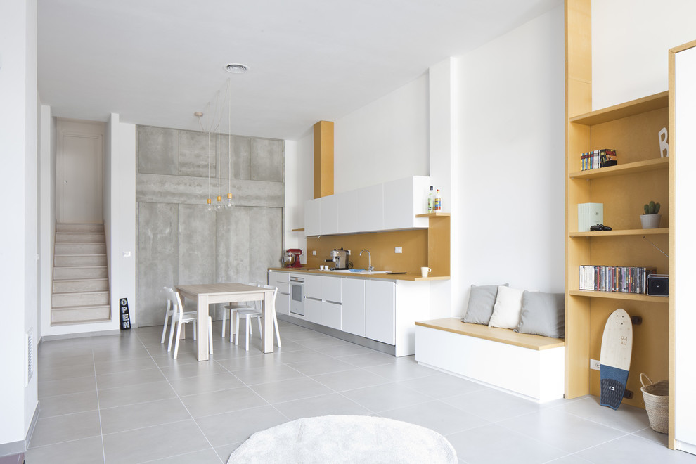 Свежая идея для дизайна: прямая кухня среднего размера в современном стиле с обеденным столом, плоскими фасадами, белыми фасадами, желтым фартуком и серым полом без острова - отличное фото интерьера