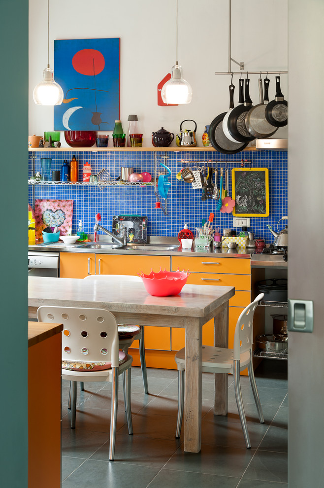 Eklektische Küche mit flächenbündigen Schrankfronten, orangefarbenen Schränken, Edelstahl-Arbeitsplatte, Küchenrückwand in Blau, Küchengeräten aus Edelstahl und grauem Boden in Turin