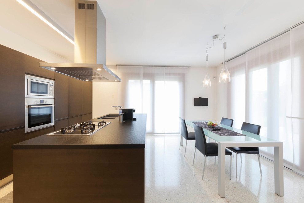 Zweizeilige Moderne Wohnküche mit Doppelwaschbecken, flächenbündigen Schrankfronten, hellbraunen Holzschränken, Küchengeräten aus Edelstahl, Kücheninsel und brauner Arbeitsplatte in Venedig