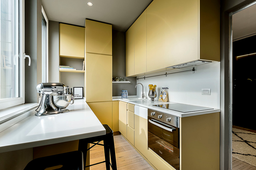 Foto di una cucina ad U design con ante grigie, elettrodomestici in acciaio inossidabile e top bianco