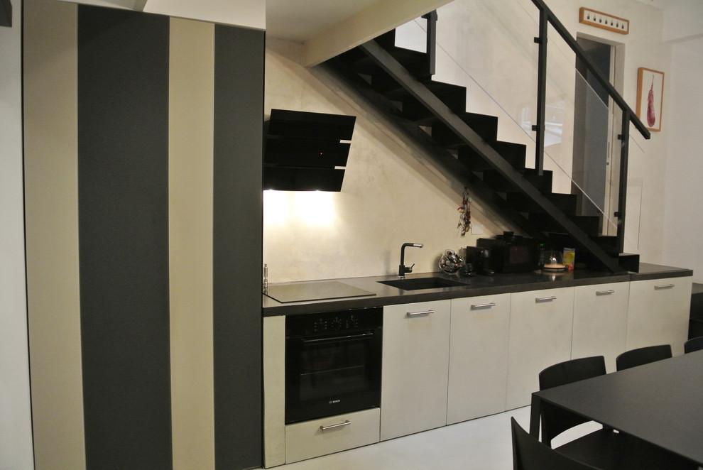 Стильный дизайн: прямая кухня среднего размера в современном стиле с врезной мойкой, черной техникой и серым полом без острова - последний тренд