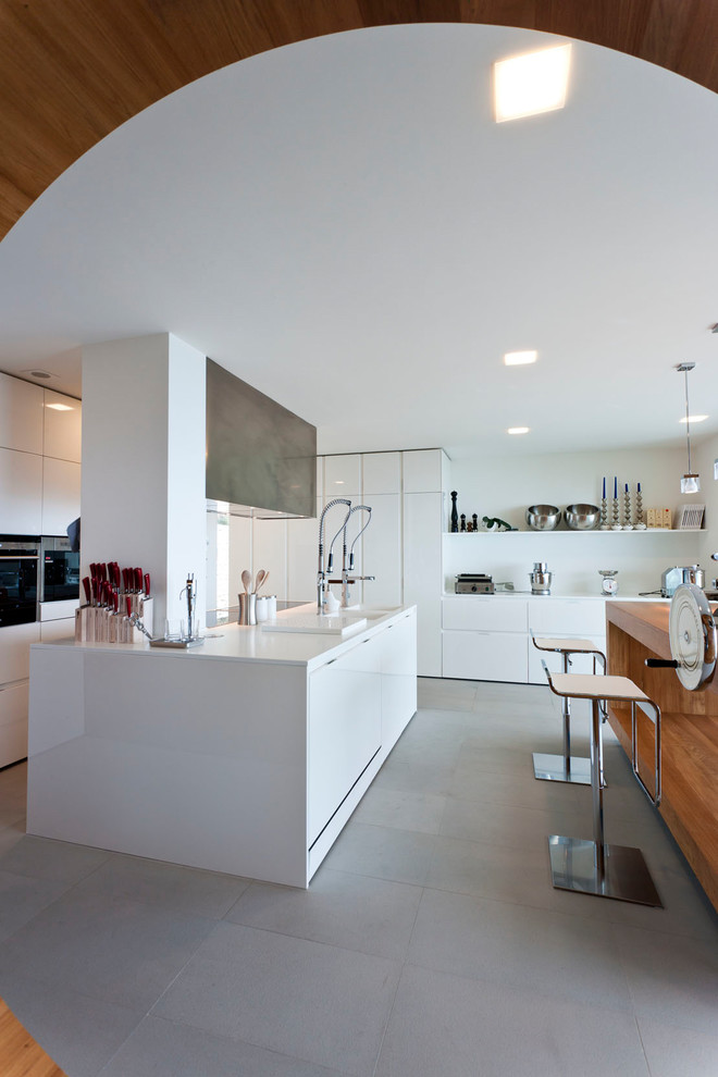 Стильный дизайн: отдельная кухня в стиле модернизм с плоскими фасадами, белыми фасадами, двумя и более островами, серым полом и белой столешницей - последний тренд