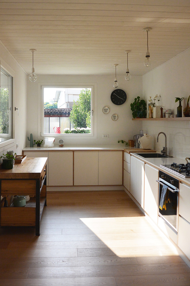 Inspiration för ett mellanstort skandinaviskt kök, med en enkel diskho, släta luckor, vita skåp, bänkskiva i kvartsit, vitt stänkskydd, stänkskydd i porslinskakel, rostfria vitvaror och ljust trägolv