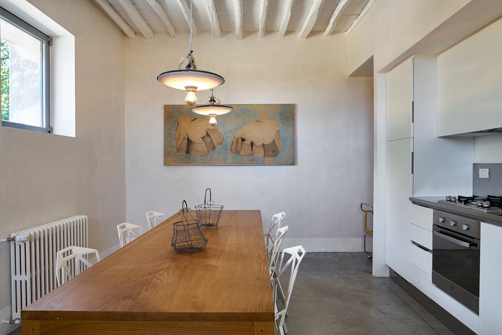 На фото: маленькая прямая кухня в стиле фьюжн с серым полом, обеденным столом, плоскими фасадами, белыми фасадами и бетонным полом для на участке и в саду с