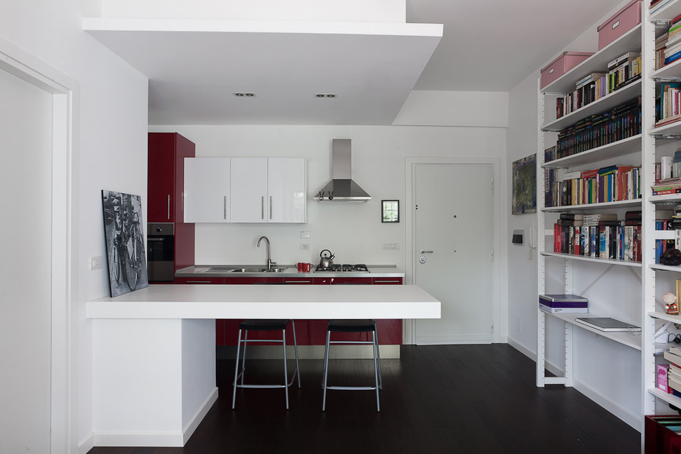 Foto på ett litet funkis linjärt kök med öppen planlösning, med en dubbel diskho, släta luckor, skåp i rostfritt stål, bänkskiva i rostfritt stål, vitt stänkskydd, rostfria vitvaror, målat trägolv, en halv köksö och svart golv