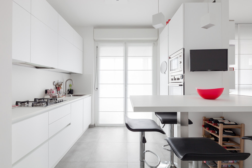 Idee per una cucina minimal di medie dimensioni con ante lisce, ante bianche, paraspruzzi bianco, penisola, pavimento grigio, top bianco e lavello a vasca singola