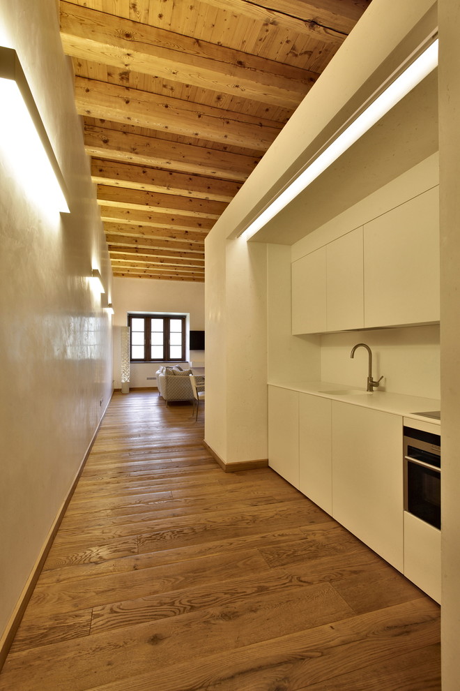 Свежая идея для дизайна: прямая кухня в стиле модернизм с плоскими фасадами, белыми фасадами и паркетным полом среднего тона - отличное фото интерьера