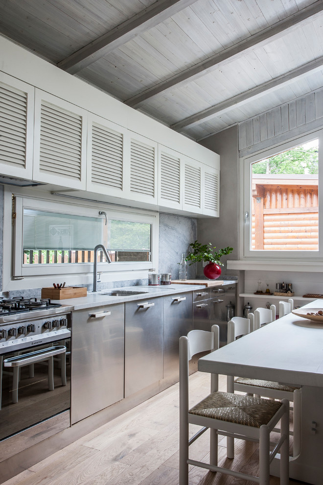 Diseño de cocina comedor lineal de estilo de casa de campo de tamaño medio sin isla con fregadero bajoencimera, armarios con puertas mallorquinas, puertas de armario blancas, electrodomésticos de acero inoxidable, suelo de madera clara y suelo beige