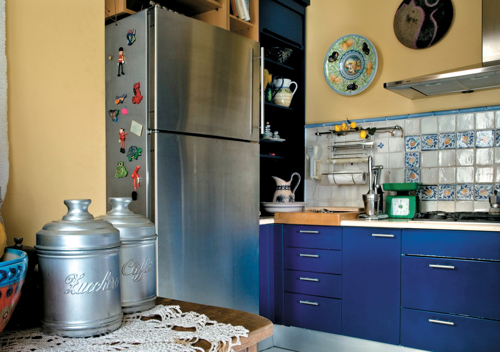 Imagen de cocina mediterránea con armarios con paneles lisos, puertas de armario azules, salpicadero de azulejos de cerámica y electrodomésticos de acero inoxidable