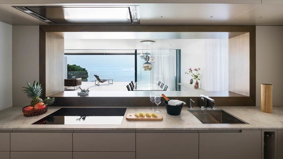 Foto di una cucina parallela minimal di medie dimensioni con lavello sottopiano, ante beige, top in marmo, penisola e top beige