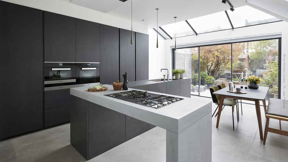 Foto di una grande cucina minimal con lavello sottopiano, ante in legno bruno e top grigio