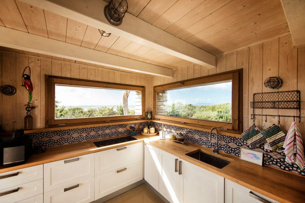 Small rural l-shaped open plan kitchen in Other with a submerged sink, recessed-panel cabinets, white cabinets, wood worktops, multi-coloured splashback, ceramic splashback, stainless steel appliances, painted wood flooring, no island, beige floors, orange worktops and exposed beams.
