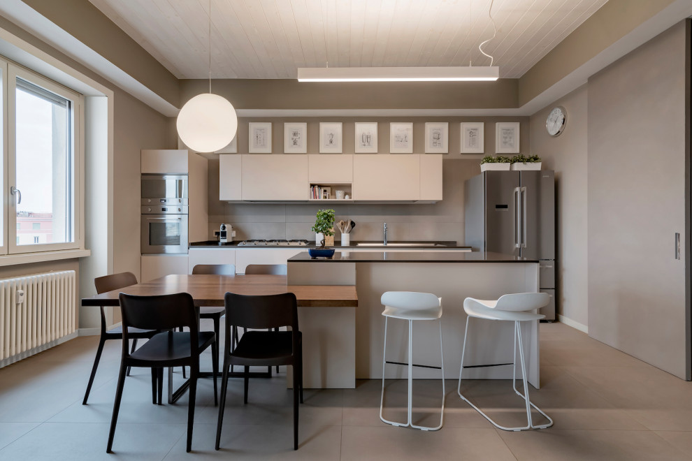 Aménagement d'une cuisine parallèle contemporaine en bois clair avec un placard à porte plane, un électroménager en acier inoxydable, sol en béton ciré, îlot, un sol gris, plan de travail noir et un plafond en bois.