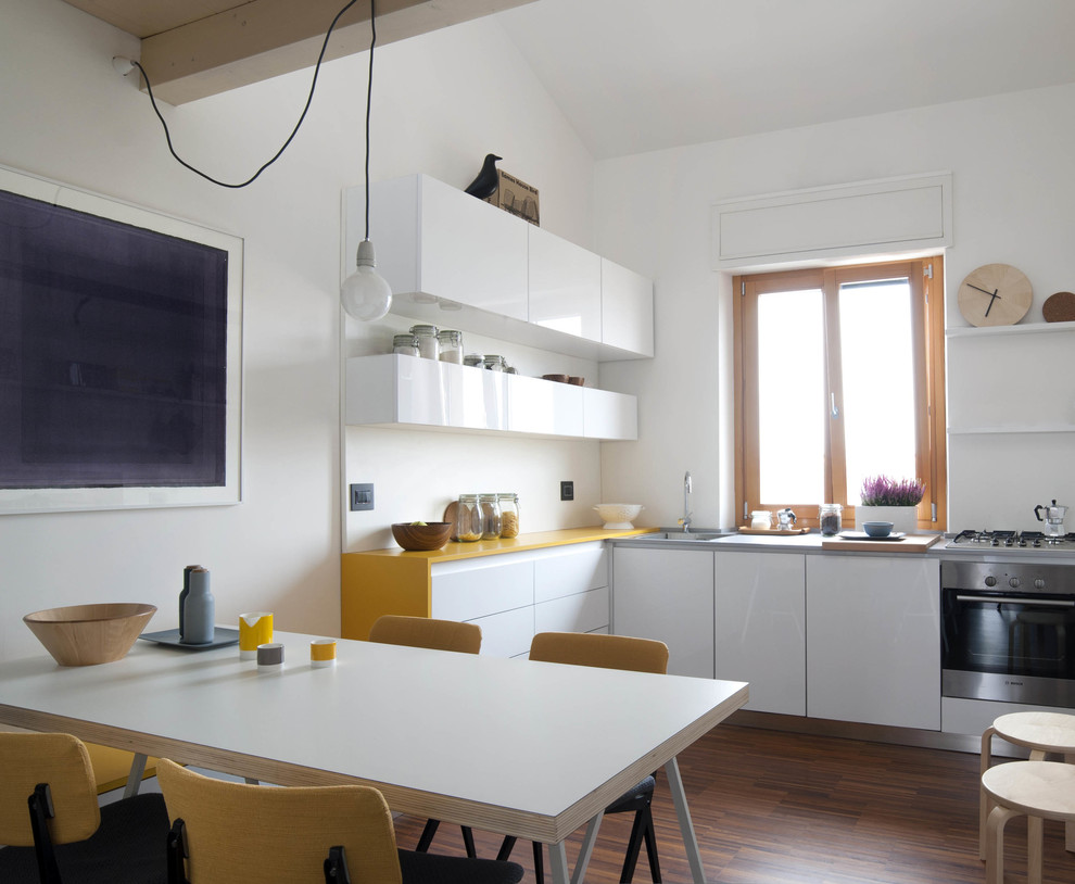 This is an example of a medium sized scandinavian l-shaped kitchen/diner in Milan with flat-panel cabinets, white cabinets, stainless steel appliances, medium hardwood flooring and yellow worktops.