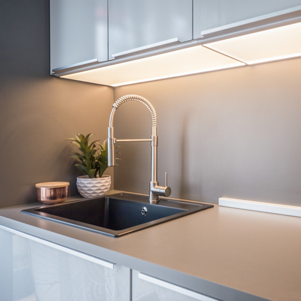 Exempel på ett litet modernt grå linjärt grått kök med öppen planlösning, med släta luckor, grå skåp, laminatbänkskiva, grått stänkskydd, rostfria vitvaror, linoleumgolv, en halv köksö, grått golv och en enkel diskho