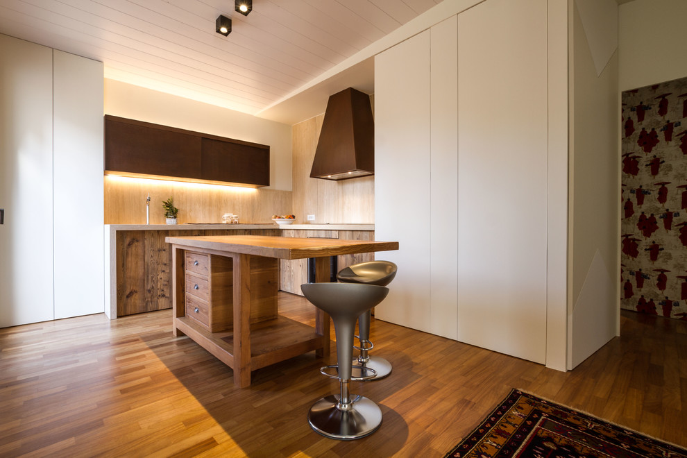 Immagine di una cucina mediterranea con ante lisce, ante in legno scuro, paraspruzzi beige, paraspruzzi in legno, pavimento in legno massello medio e pavimento marrone