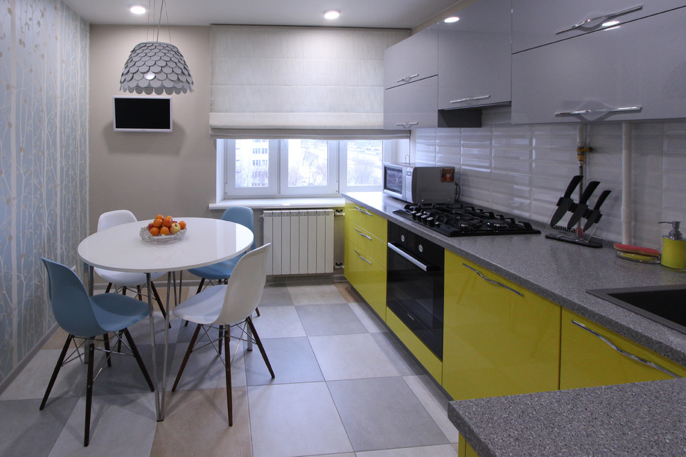 Immagine di una piccola cucina a L design chiusa con lavello da incasso, ante lisce, ante grigie, top in laminato, paraspruzzi bianco, paraspruzzi con piastrelle in ceramica, elettrodomestici neri, pavimento in gres porcellanato, nessuna isola, pavimento multicolore e top grigio