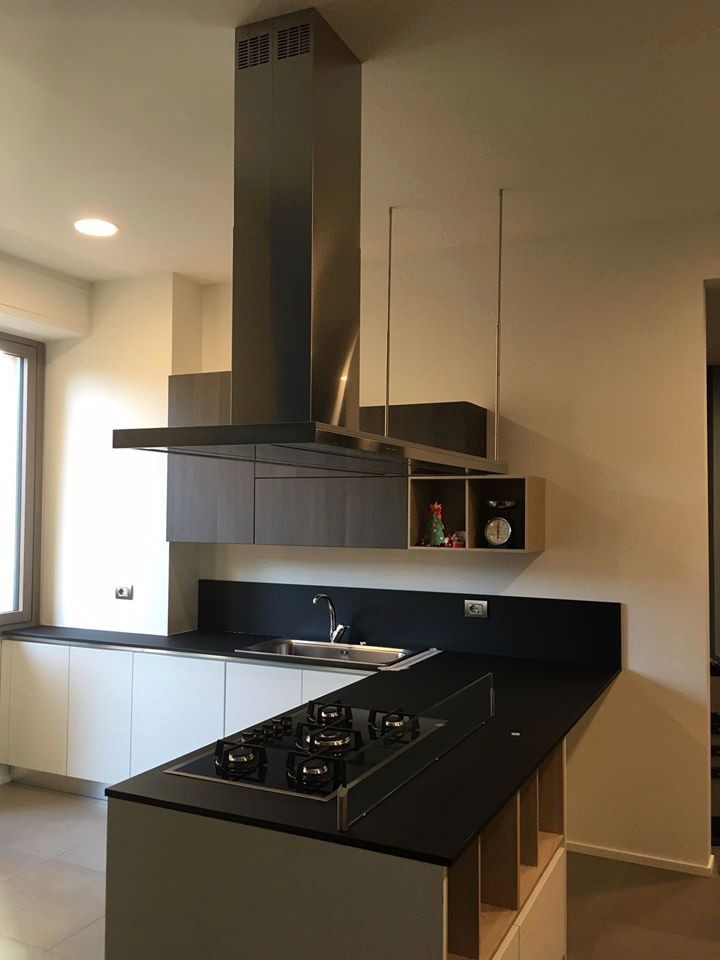 Foto di una grande cucina design con ante lisce, ante bianche, top in laminato, penisola e top nero