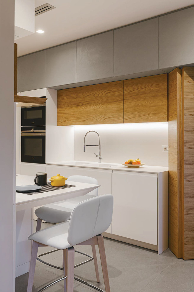 Immagine di una cucina parallela design chiusa con ante lisce, ante bianche, nessuna isola, pavimento grigio e top bianco