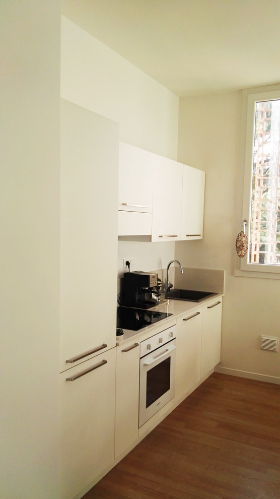 Exempel på ett mellanstort modernt linjärt kök och matrum, med en enkel diskho, släta luckor, vita skåp, granitbänkskiva, vitt stänkskydd, stänkskydd i sten, vita vitvaror och ljust trägolv