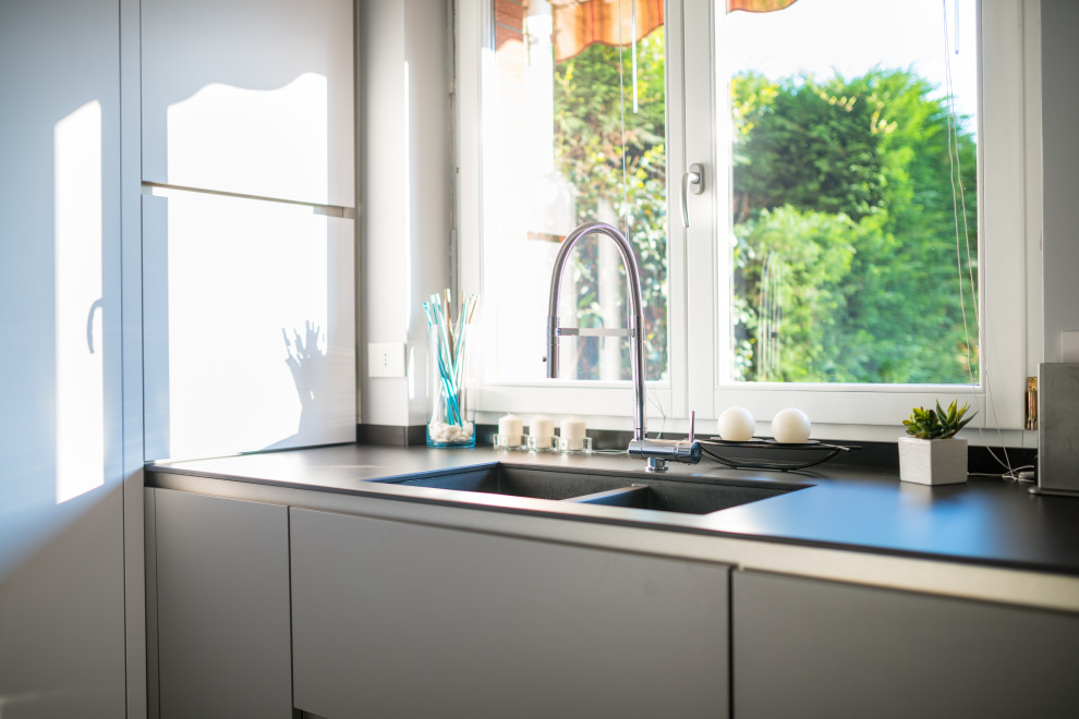 Foto di una cucina minimalista di medie dimensioni con lavello a doppia vasca, ante grigie, top in laminato, pavimento in gres porcellanato, pavimento grigio e top grigio