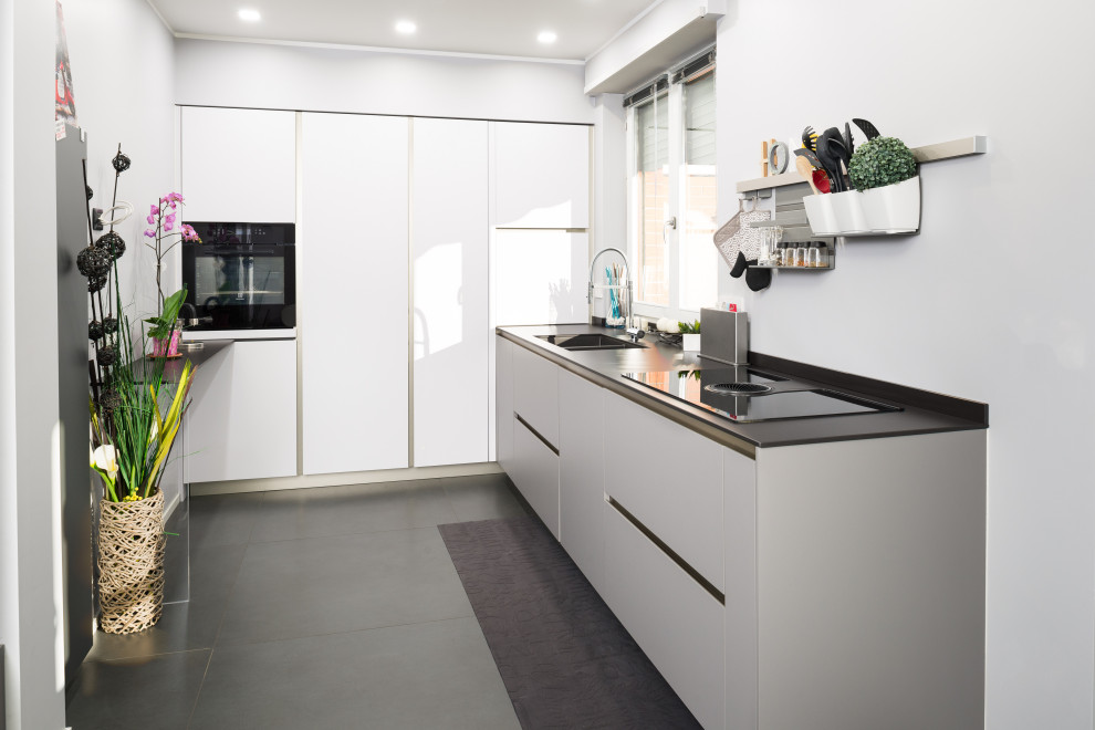 Idéer för att renovera ett mellanstort, avskilt funkis svart svart l-kök, med grått golv, en nedsänkt diskho, släta luckor, grå skåp, bänkskiva i koppar, svarta vitvaror och klinkergolv i porslin