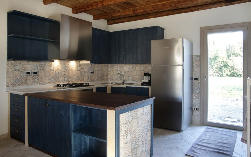 ヴェネツィアにある高級な中くらいな地中海スタイルのおしゃれなキッチン (ダブルシンク、青いキャビネット、クオーツストーンカウンター、マルチカラーのキッチンパネル、セラミックタイルのキッチンパネル、シルバーの調理設備、セラミックタイルの床、ベージュの床、ベージュのキッチンカウンター) の写真